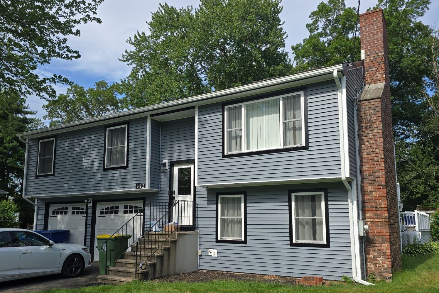 A blue raised-ranch home with new vinyl siding and attached garage