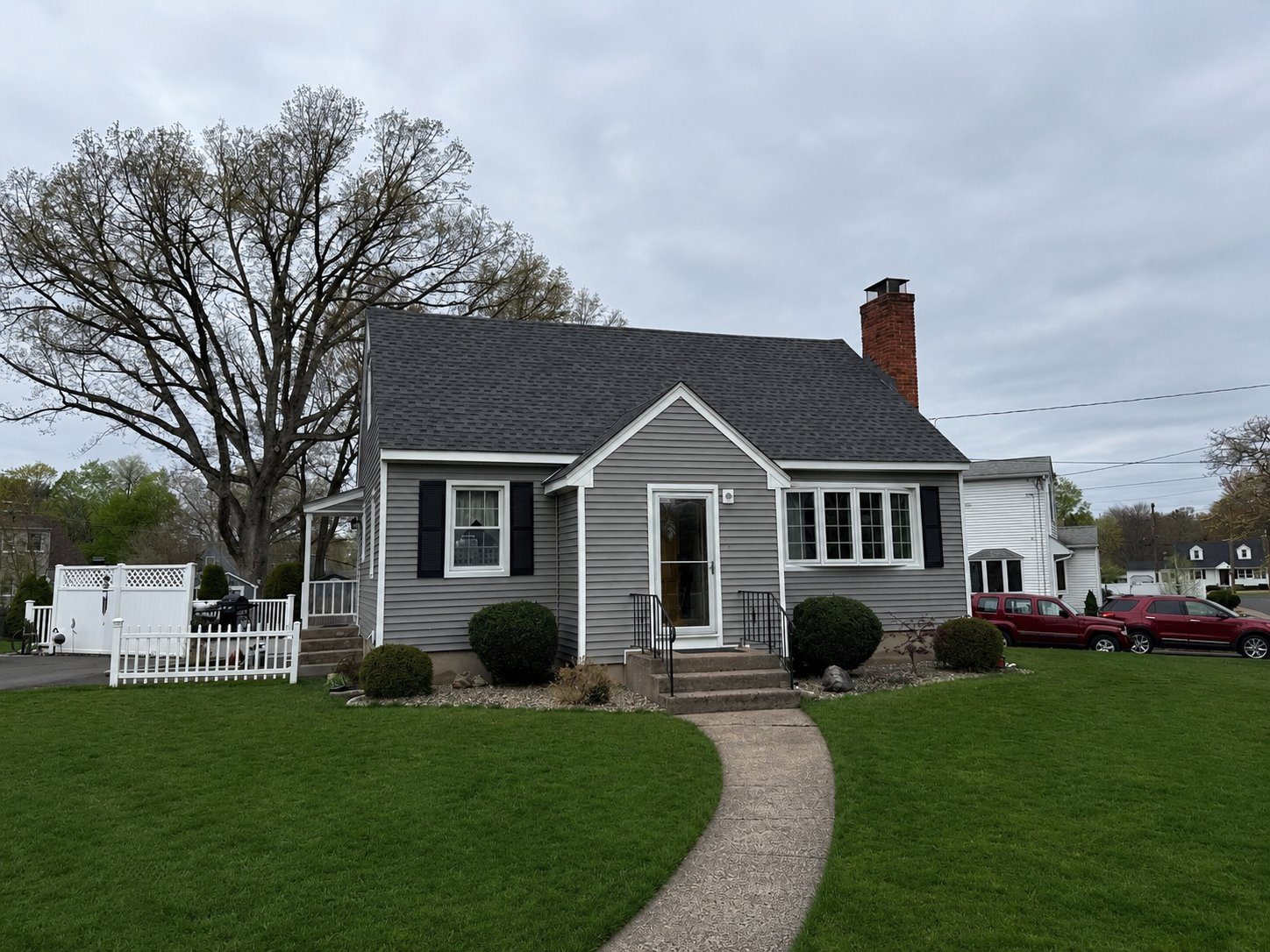 A gray home with a new roof and landscaped front yard