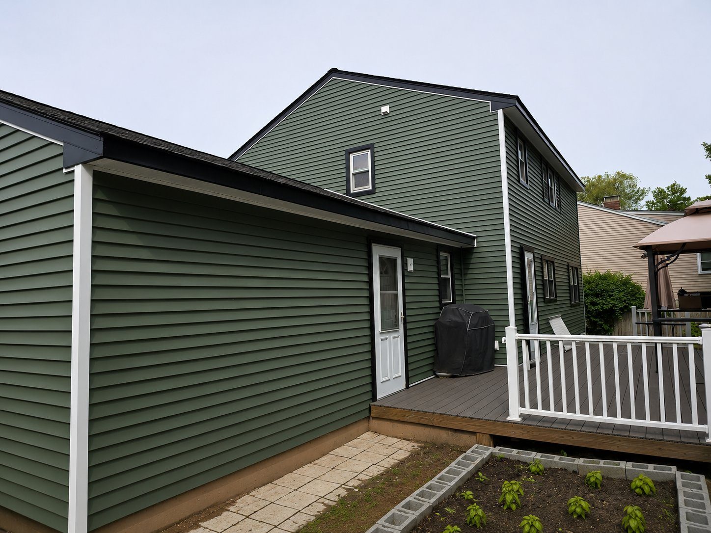 A home with new green vinyl siding and a newly built deck